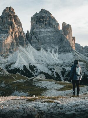 A hiker admires the majestic Tre Cime di Lavaredo in the Italian Dolomites, perfect for travel enthusiasts.