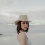 A young woman in a sun hat gazes over her shoulder at a beach on the Gold Coast, Australia.
